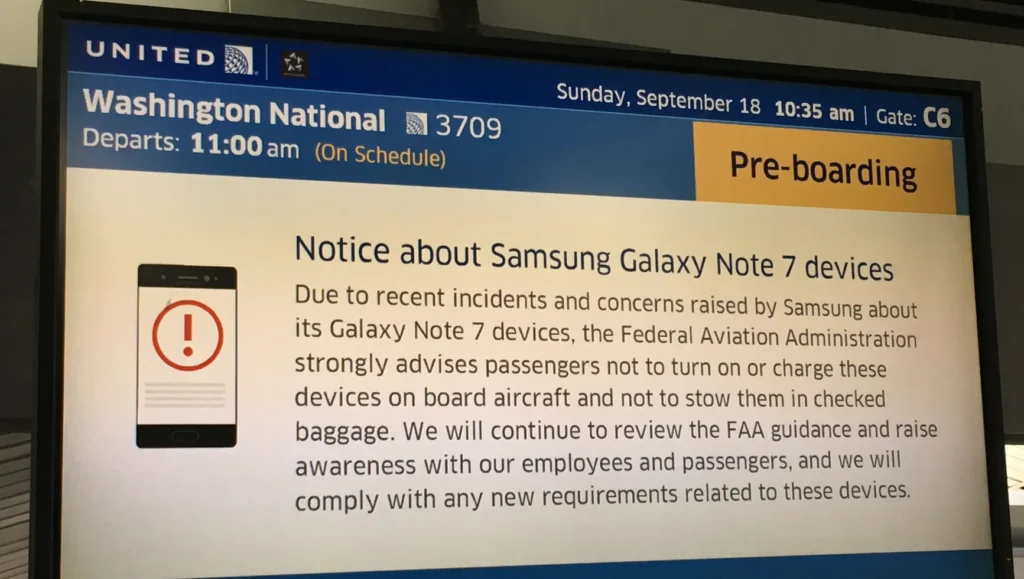 An airport gate display shows a pre-boarding notice warning passengers not to turn on or charge Samsung Galaxy Note 7 devices due to safety concerns, with a flight to Washington National at 11:00 am on September 18.